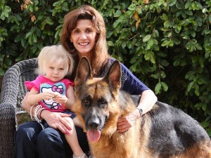 Woman, child, and dog sitting outside together.