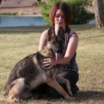 A woman sitting on the ground with her dog.