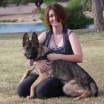 A woman sitting on the ground with her dog.