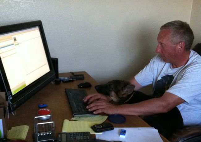 Man and dog at computer desk together.
