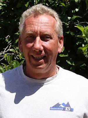 Smiling man in a white shirt outdoors.
