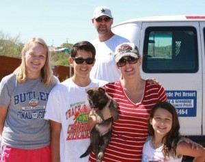 A family posing for the camera in front of their van.