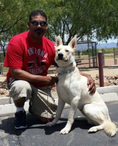 Man with dog outdoors on sunny day.