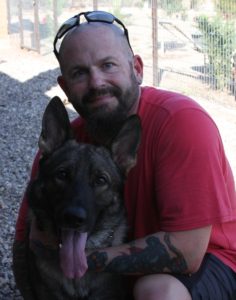 Man with dog outside near fence.
