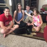 A group of people sitting on the floor with a cat.