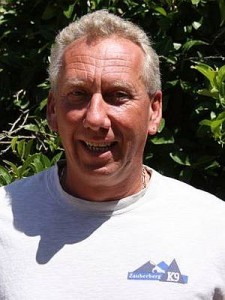 Smiling man outdoors in casual white shirt.