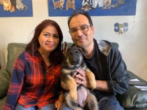 A man and woman holding a dog in their arms.