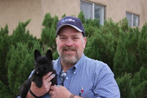 A man holding a black dog in his hands.