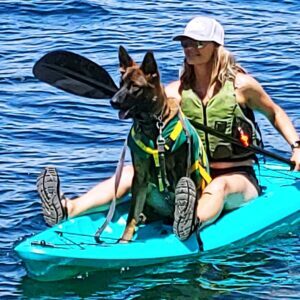 A woman and her dog are kayaking in the water.
