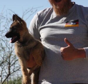 A man holding a dog with one paw raised.