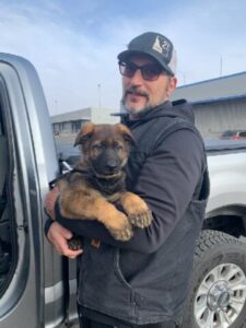 A man holding his dog in the back of a truck.