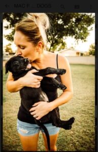 A woman holding a black dog in her arms.