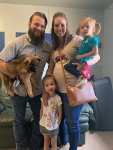 A family posing for the camera with their dog.